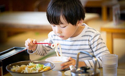 子どもがうどんを食べている写真