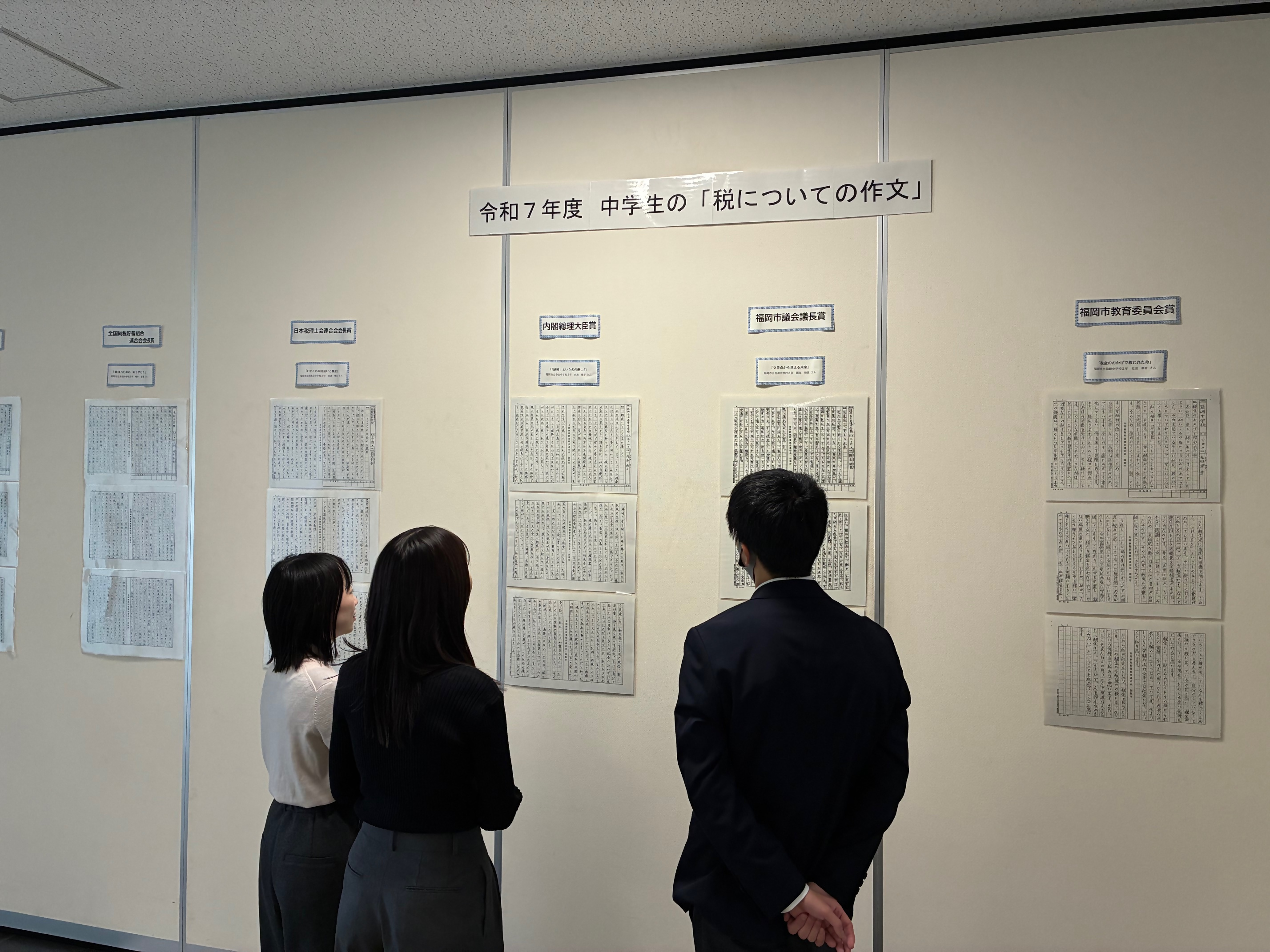 パネル展の様子。中学生の「税についての作文」の展示コーナーを見ている方の写真